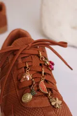 Zapatillas bajas color marrón con cordones y charms dorados.