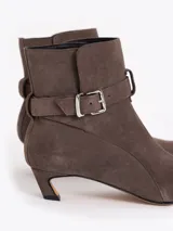 Bota de caña media confeccionada en cuero descarne, con punta fina, taco bajo forrado y detalle de tira con hebilla metálica en el tobillo.