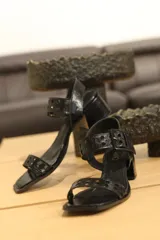 Sandalias negras de cuero charol con taco cuadrado y tira ancha con perforaciones.