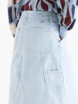Pollera midi de denim en color azul claro con efecto lavado. Presenta un diseño de corte recto con costuras decorativas visibles, bolsillos frontales tipo cargo y una abertura central en el ruedo.