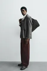 Pantalón de hombre color bordó oscuro, de corte ancho (wide fit), confeccionado en tejido de algodón con acabado flocada o efecto aterciopelado. Presenta cinco bolsillos y cierre frontal con cremallera y botón.