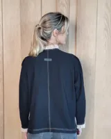 Camisa de manga larga con estampado de rayas verticales en tonos crudo y beige. Presenta cuello alto con volados, cierre frontal con botones dobles y puños con volados.