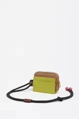 Monedero compacto de Bimba y Lola en color negro, con cierre de cremallera y cordón ajustable con nudos decorativos. Presenta el logo de la marca estampado en letras doradas en la parte frontal.