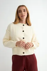 Cardigan de punto color marrón chocolate, con cuello redondo, cierre frontal de botones y diseño de costuras verticales visibles. Presenta puños y ruedo acanalados.