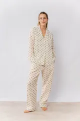 Pijama de algodón estampado con motas verdes y marrones, compuesto por una camisa de manga larga abotonada y un pantalón con elástico en la cintura y dos bolsillos.