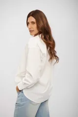 Camisa de corte clásico y silueta holgada, con cuello camisero, cierre frontal de botones y mangas largas con puños abotonados.