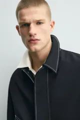 Sobrecamisa de corte regular fit color negro con pespuntes en contraste blancos. Presenta cuello solapa, mangas largas con puños abotonados, bolsillos frontales de vivo y cierre de cremallera oculta por solapa con botones.