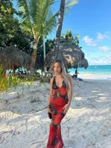 Vestido midi de microtul rojo con estampado de rosas y hojas verdes, escote en V con encaje negro y breteles finos regulables en la espalda.