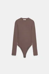Body de manga larga con cuello redondo, confeccionado en una mezcla de algodón y modal. Presenta cierre inferior con botones a presión.