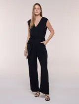 Enterito de crepe negro marca Luxology, sin mangas, con escote cruzado en V, cintura elastizada con lazo de ajuste y pantalón de corte amplio.