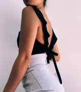 Crop top negro con textura brillante, breteles anchos con volados y espalda descubierta que se ata con lazos.