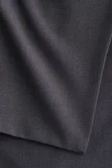 Pantalón acampanado de tiro alto con pollera mini integrada en la cintura, confeccionado en tela lisa de color gris oscuro.
