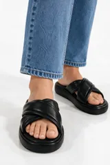 Sandalias planas color negro con tiras acolchadas cruzadas en el empeine y suela de goma con plataforma baja.