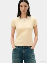 Remera de corte slim color beige, confeccionada en punto de algodón elástico, con cuello redondo y logo texturizado en fuente Script en el pecho.