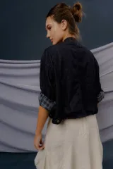 Campera de denim azul oscuro, de corte corto y estilo bomber, con cierre frontal y detalles de forrería a cuadros visibles en el interior de los puños.