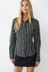 Camisa de manga larga con estampado de rayas verticales en tonos verde claro y negro. Presenta un corte ajustado (slim fit), cuello clásico, cierre frontal de botones y puños anchos a rayas.