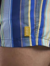 Short de baño con estampado botánico en tonos naranja y coral, con cintura elástica ajustable mediante cordón y malla interior para mayor soporte.