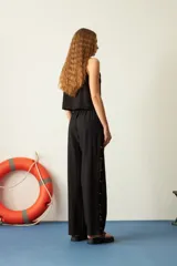 Pantalón marrón de corte recto, con cintura elastizada y cordón ajustable. Presenta mostacillas decorativas en los laterales.