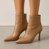 Botas de cuero sintético color beige con punta fina y tacón de aguja.