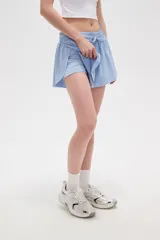 Short de poliéster color celeste, de calce holgado y tiro alto, con cintura elástica ajustable mediante cordón y bolsillos laterales.