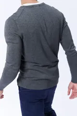Buzo de punto gris melange con escote en V, de manga larga y puños acanalados.