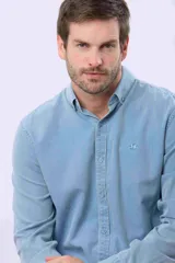 Camisa de manga larga con efecto lavado de color celeste, con cuello camisero, cierre frontal de botones y bordado pequeño en el pecho.