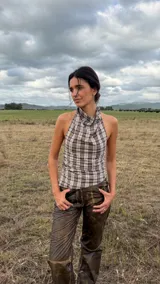Top de cuello halter con diseño drapeado en el frente, confeccionado en tela con estampado de cuadros. Presenta un ajuste entallado con elásticos laterales y espalda descubierta.