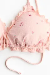 Top de bikini de triángulo con ribetes sobrehilados, breteles ajustables y copas con relleno extraíble, de color rosado con estampado floreado.