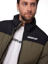 Campera puffer Caterpillar de corte estándar, con diseño bicolor en verde oliva y negro. Presenta cuello alto, cierre frontal con cremallera, bolsillos laterales con cierre y logo de la marca estampado en el pecho.