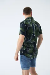 Camisa de manga corta con estampado botánico de hojas en tonos azul y blanco. Presenta cuello clásico, cierre frontal abotonado y corte slim.