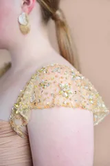 Vestido largo de fiesta color oro, confeccionado en gasa de seda natural con corsé drapeado, mangas y faja en tul bordado.