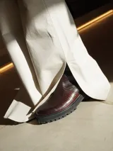 Botas de cuero con textura simil cocodrilo en color marrón, diseño de caña baja con cierre lateral y suela track negra de goma.