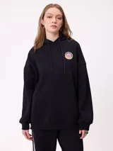 Canguro gris con capucha, de corte oversize, con estampado gráfico multicolor en la espalda que incluye diversos parches y logotipos de la marca Rusty.