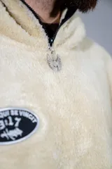 Canguro de peluche color crema, con cuello alto y cierre frontal parcial. Presenta un parche ovalado con diseño gráfico en el pecho y un bolsillo frontal tipo canguro.