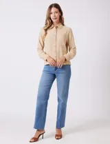 Camisa de crepe color beige con cuello clásico, cierre frontal con botones y dos bolsillos aplicados en el pecho.