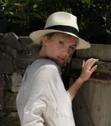 Sombrero tipo Panamá de paja color natural, con cinta negra alrededor de la copa.