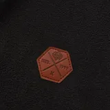 Campera polar Hurley modelo Terra, color negro, con cuello alto, cierre frontal completo, bolsillos laterales y un parche hexagonal de cuero sintético en el pecho.