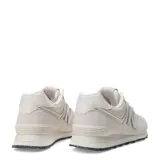 Championes urbanos New Balance modelo 574, color marfil, confeccionados en gamuza y malla con detalles texturizados en la puntera. Presentan el logo N característico en los laterales y suela con diseño moteado.