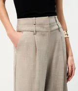 Pantalón de sastrería de corte ancho y recto, color gris, con cintura doble estructurada y removible, pinzas frontales y bolsillos.