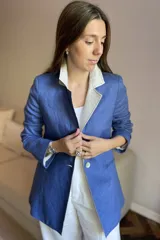 Blazer azul de lino con corte entallado, cuello y solapas combinadas en color gris, cierre con botón de nácar, bolsillos laterales y tajo en la espalda.