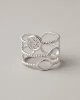 Anillo triple ajustable de acero quirúrgico plateado con detalles de circonias, compuesto por tres bandas: una con un dije circular pavé, otra con aros ovalados y otra con textura de esferas.