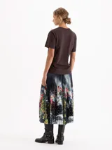 Pollera midi plisada con estampa digital artística y detalles de círculos calados. Presenta una cintura con elástico negro a la vista.