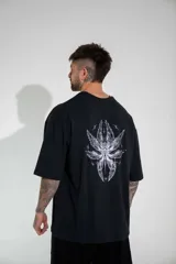 Remera oversize de algodón elastizado en color negro, con diseño gráfico estampado en la espalda que presenta motivos alados y elementos celestiales.