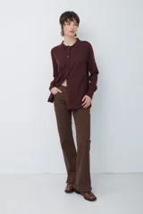Cardigan de punto color beige, con cuello camisero, cierre frontal de botones y bolsillo aplicado en el pecho. Presenta mangas largas con puños acanalados y un corte recto y holgado.