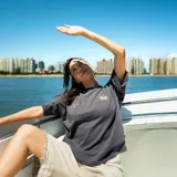 Remera gris de corte oversize con cuello redondo y mangas cortas. Estampado en la espalda con una estrella delineada en blanco, la palabra "Venefo" en amarillo y la frase "Pray to your father who is in the secret place" en letras blancas.