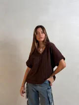 Chaleco de punto color marrón chocolate, con cuello en V y mangas cortas. Presenta un diseño de tejido con textura de trenzas verticales y un corte holgado.