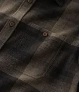 Camisa de manga larga con diseño de cuadros en tonos marrones, confeccionada en algodón. Presenta cuello camisero, cierre frontal con botones y un bolsillo en el pecho con botón.
