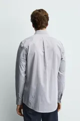 Camisa de corte regular fit confeccionada en tejido de algodón con estampado de microcuadros. Presenta cuello abotonado, manga larga con puños abotonados y cierre frontal de botones.