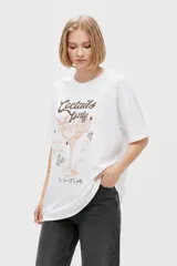 Remera de algodón blanca de corte holgado, con mangas cortas, cuello redondo a la base y estampado frontal con temática de cóctel y tipografía.