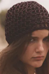 Gorro tipo casquete de tejido trenzado con diseño de red, en color marrón oscuro.